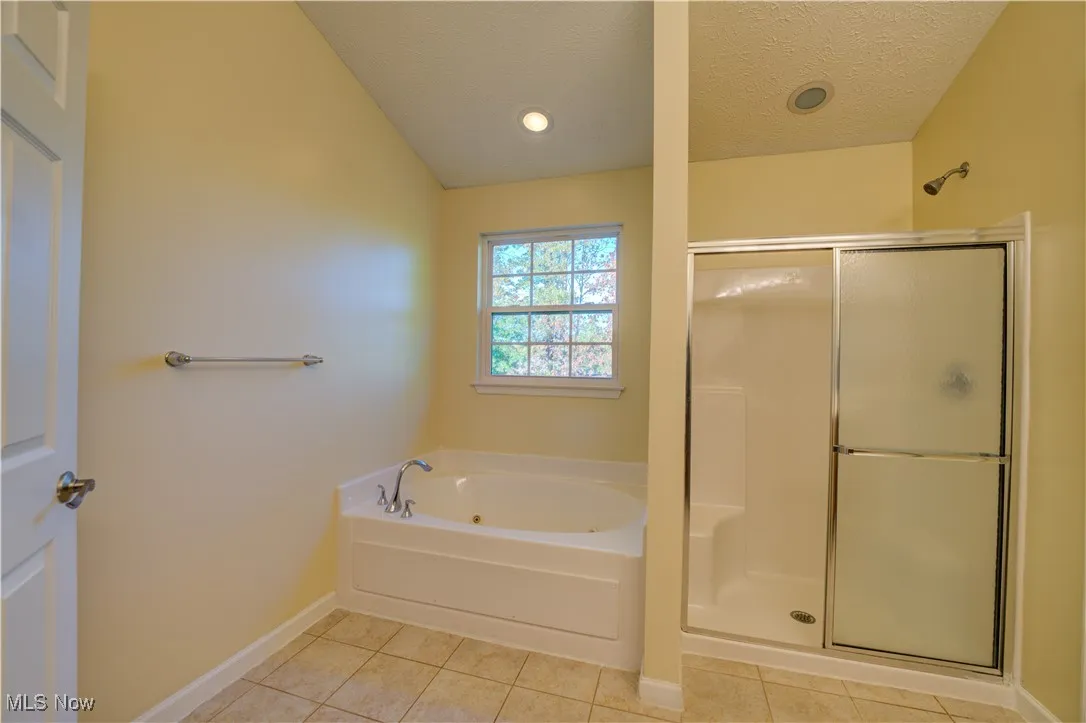 Bathroom featuring light tile patterned floors, a stall shower, a garden tub, a textured ceiling, and recessed lighting
