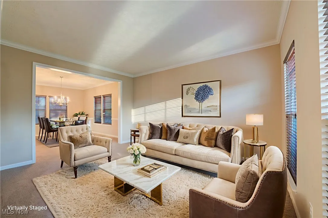 Carpeted living area featuring crown molding and a chandelier
