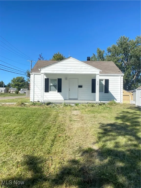 Front view of property with a lawn, a porch, and roof with shingles