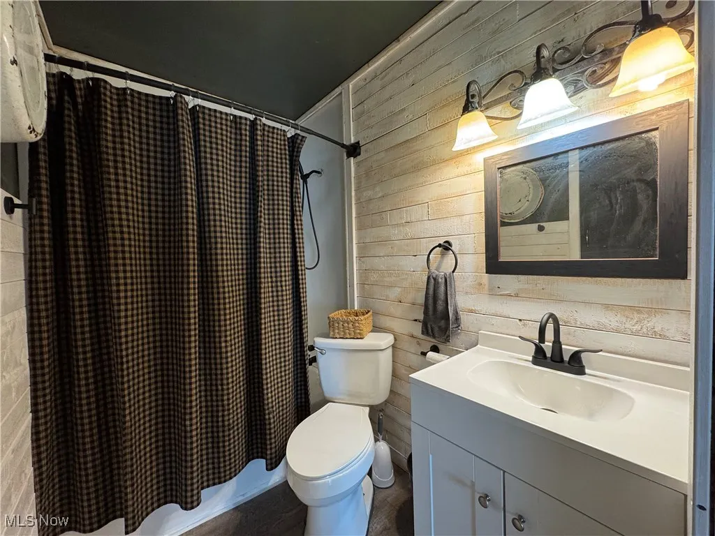 Bathroom with wood walls, vanity, and shower / bath combo