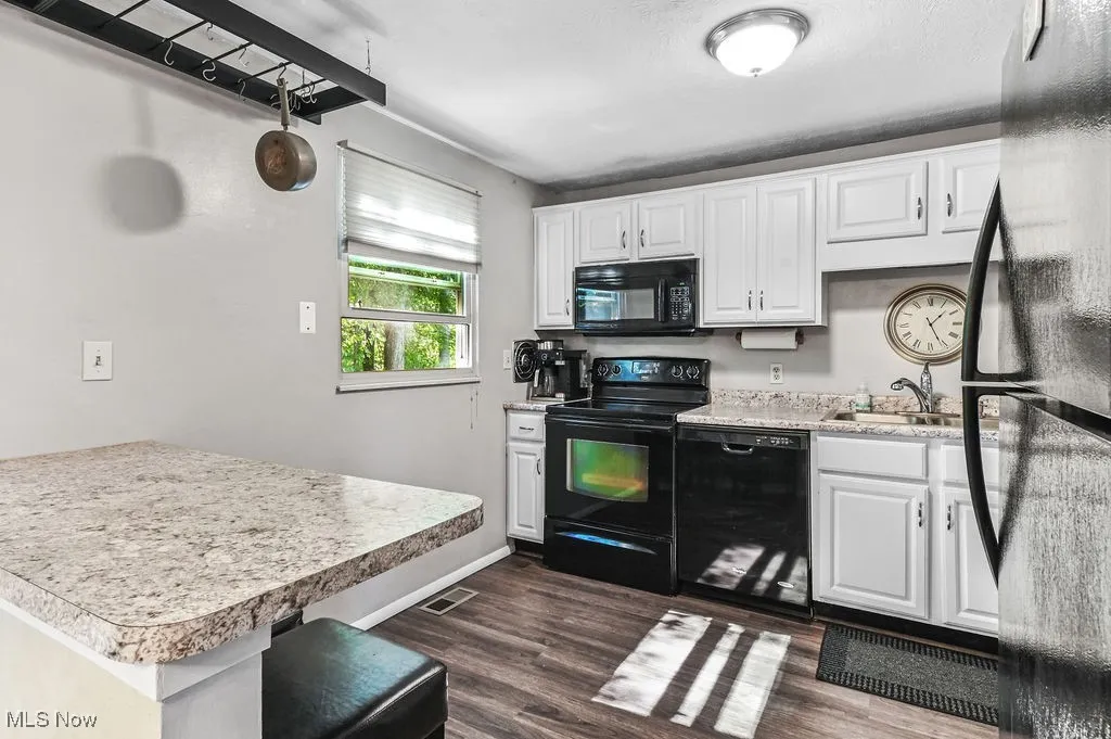Kitchen featuring black appliances, white cabinets, dark wood-type flooring, and light countertops