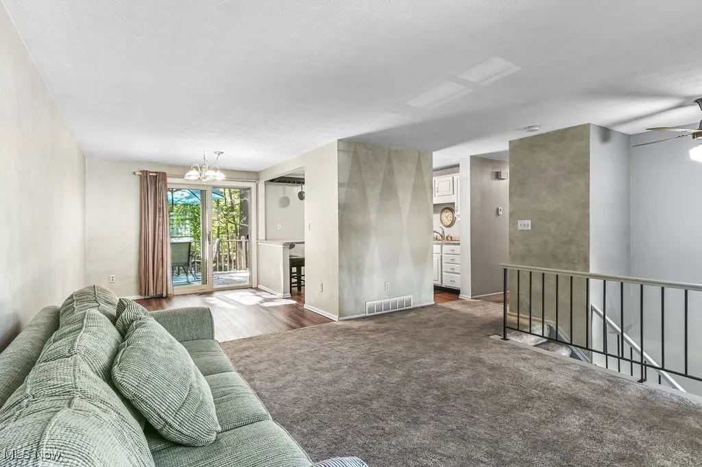 Carpeted living area with a chandelier and ceiling fan