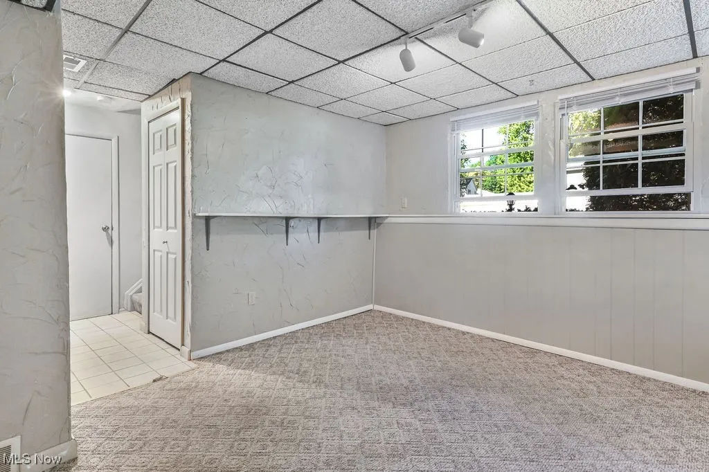 Family room with a drop ceiling and light colored carpet