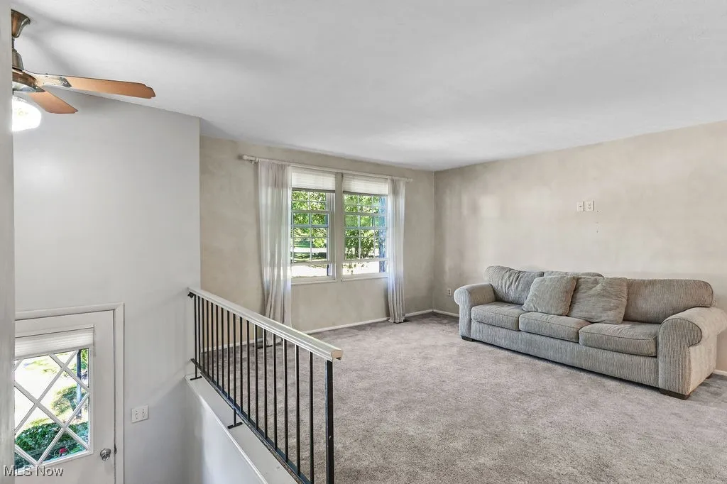 Carpeted living room featuring plenty of natural light and a ceiling fan