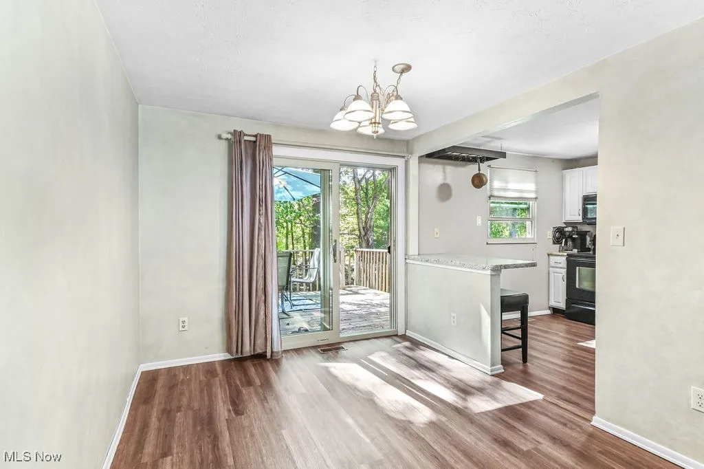 Unfurnished dining area featuring dark wood finished floors and a chandelier