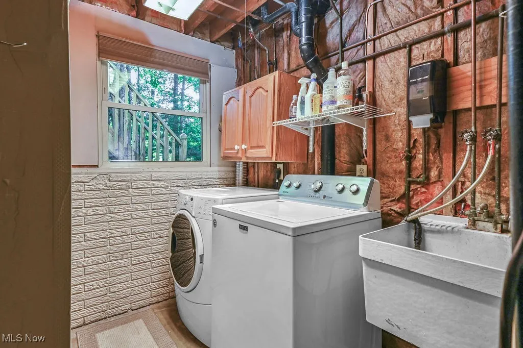 Washroom featuring tile walls, separate washer and dryer, and cabinet space