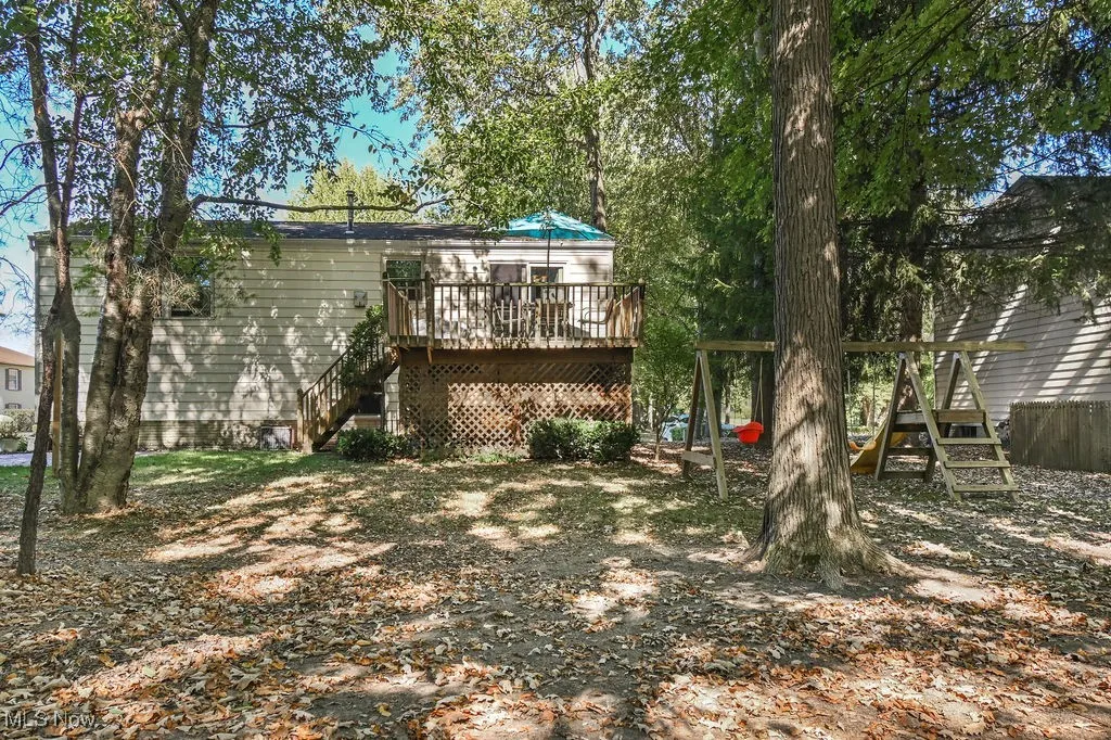 Rear view of house featuring a deck, stairway, and a playground