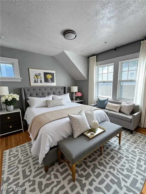 Bedroom featuring wood finished floors, multiple windows, and a textured ceiling