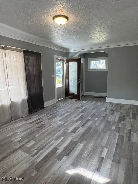 Foyer featuring crown molding, wood finished floors, arched walkways, and a textured ceiling