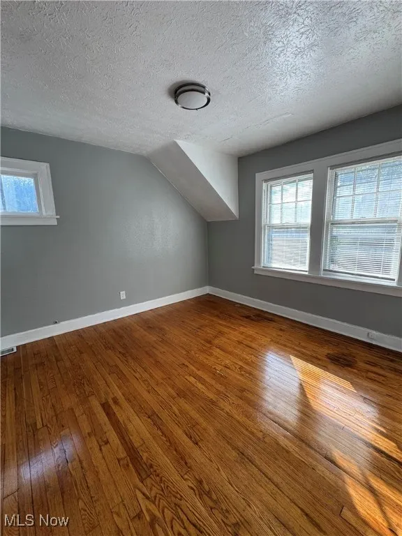 Bonus room with wood-type flooring and a textured ceiling