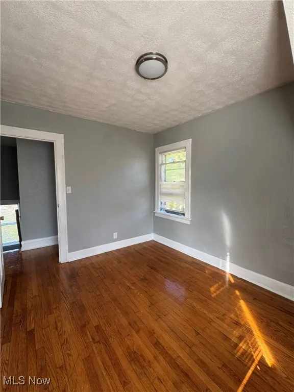 Spare room with a textured ceiling and dark wood-type flooring