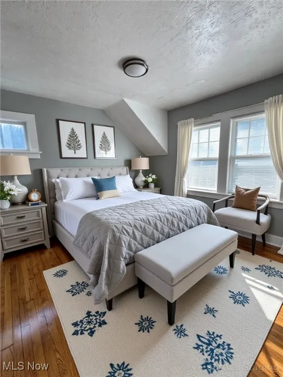 Bedroom featuring hardwood / wood-style flooring, multiple windows, and a textured ceiling
