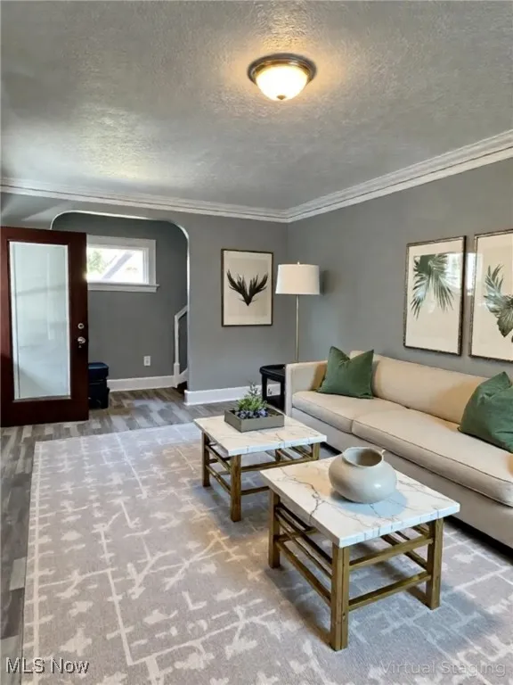 Living area with arched walkways, a textured ceiling, and ornamental molding