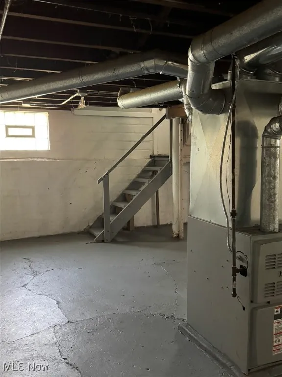 Below grade area featuring stairway and heating unit