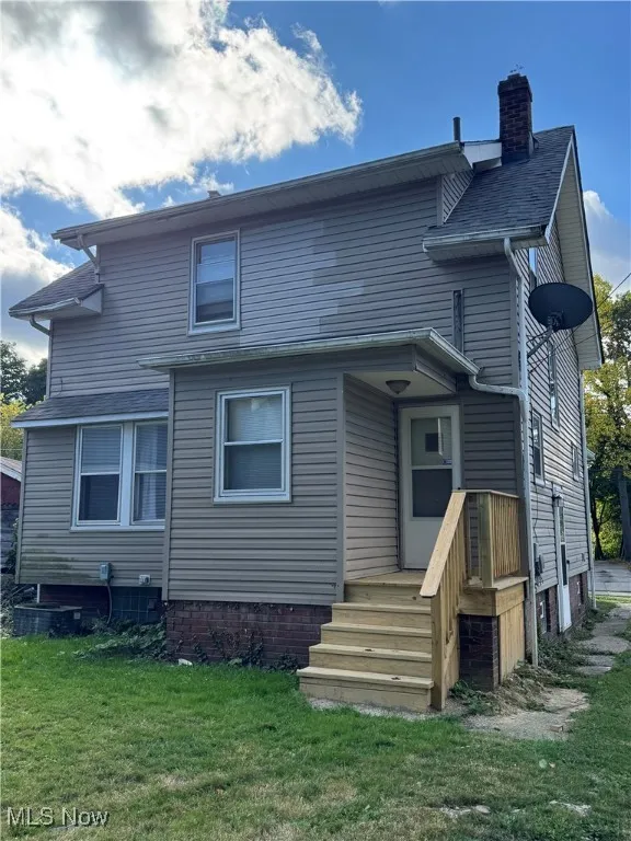 Rear view of house featuring a lawn and a chimney