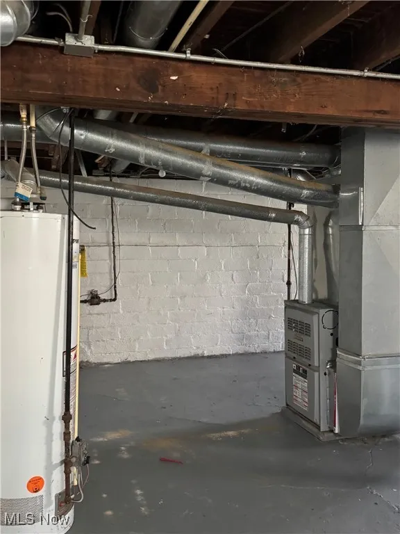 Unfinished below grade area featuring gas water heater and heating unit