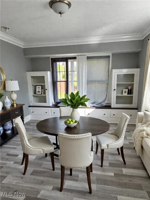 Dining space featuring ornamental molding, light wood-type flooring, and a textured ceiling