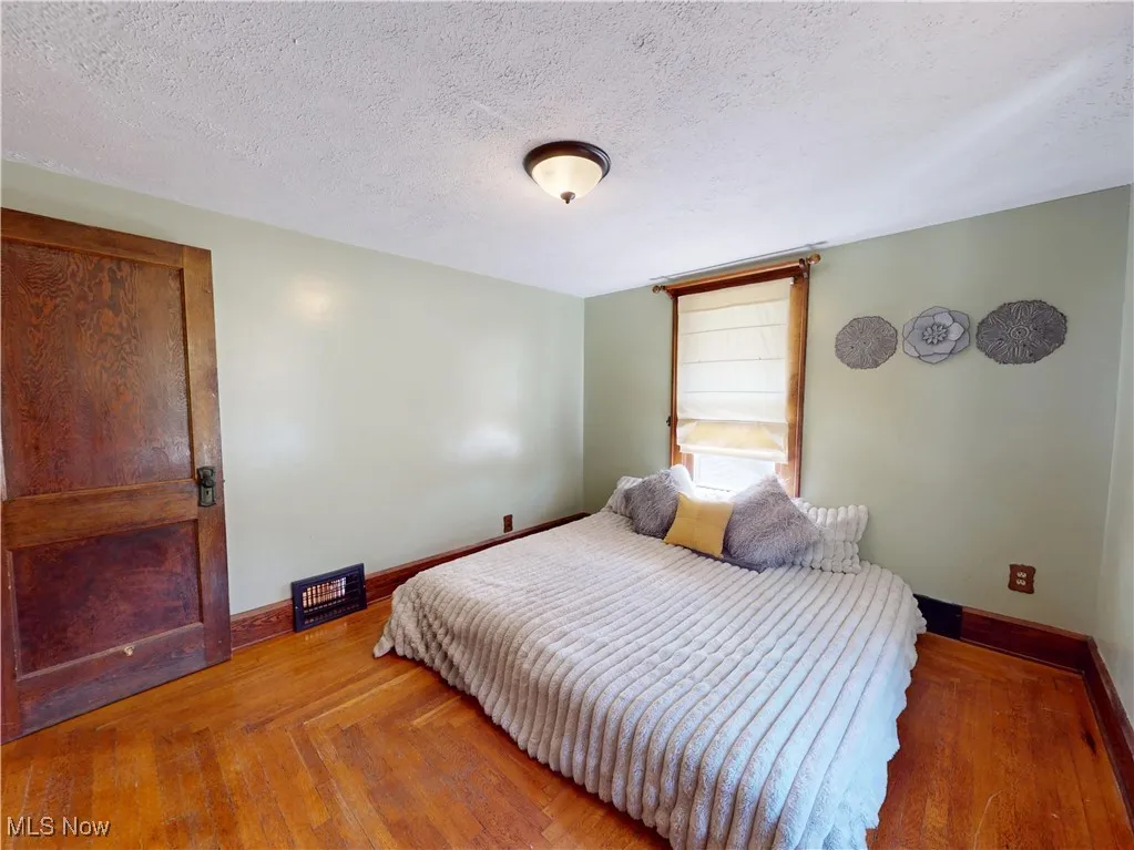 Primary bedroom featuring a textured ceiling and hardwood flooring
