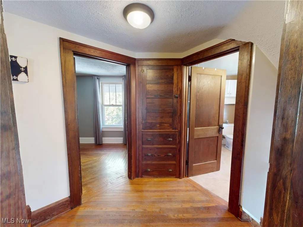 Hallway featuring a textured ceiling and hardwood flooring