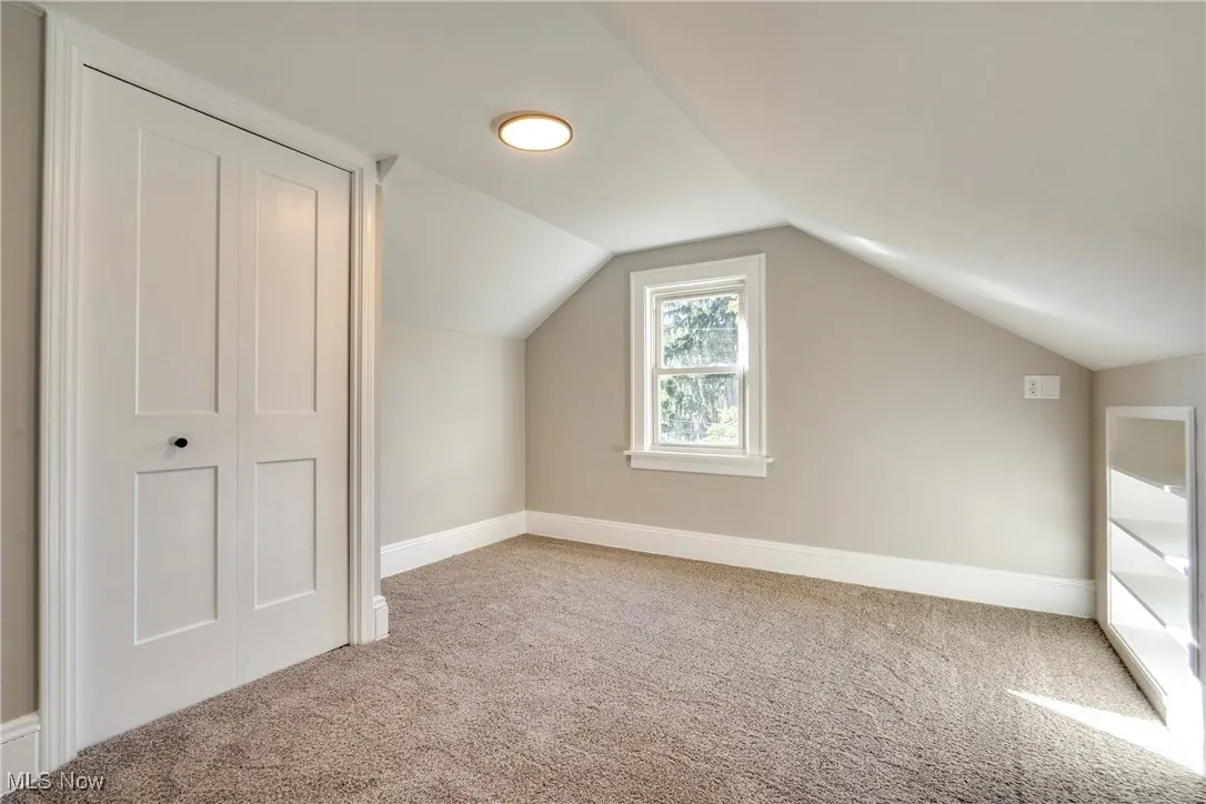 Additional living space with vaulted ceiling and light carpet