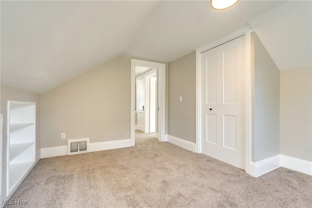 Additional living space featuring lofted ceiling and carpet