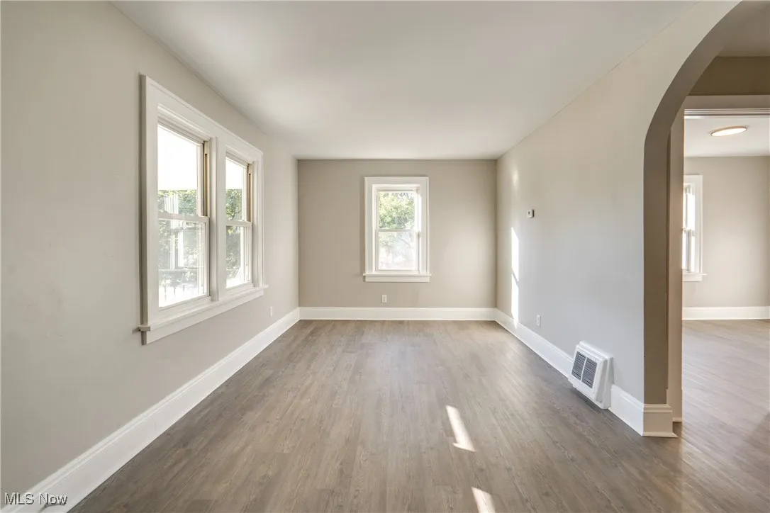 Empty room featuring arched walkways and wood finished floors