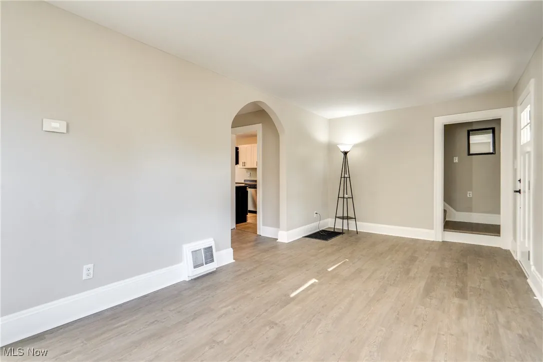 Empty room featuring arched walkways and light wood-style flooring
