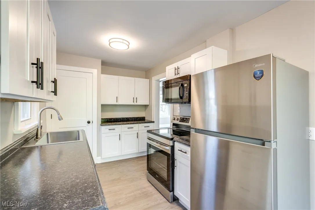 Kitchen with stainless steel appliances, white cabinetry, healthy amount of natural light, and light wood finished floors