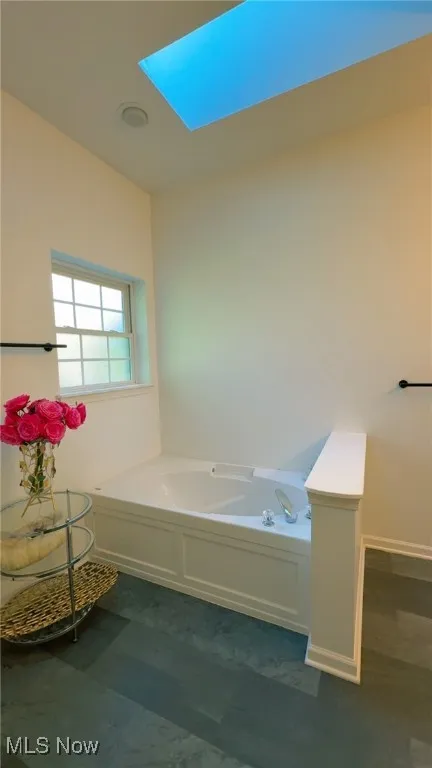Full bath featuring a garden tub and a skylight