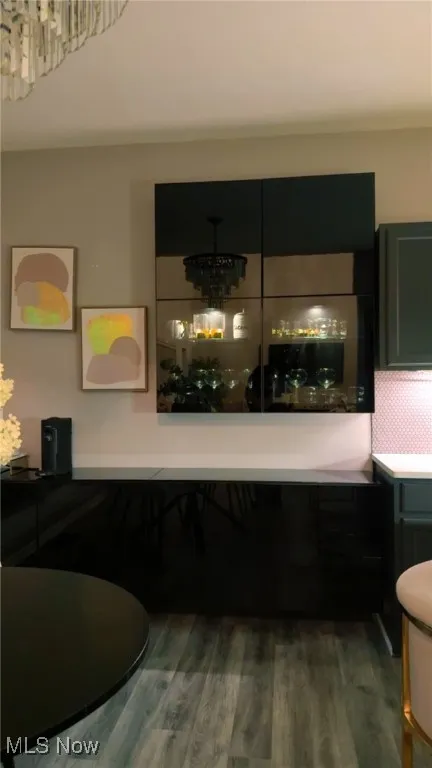 Space with a chandelier and dark wood-type flooring