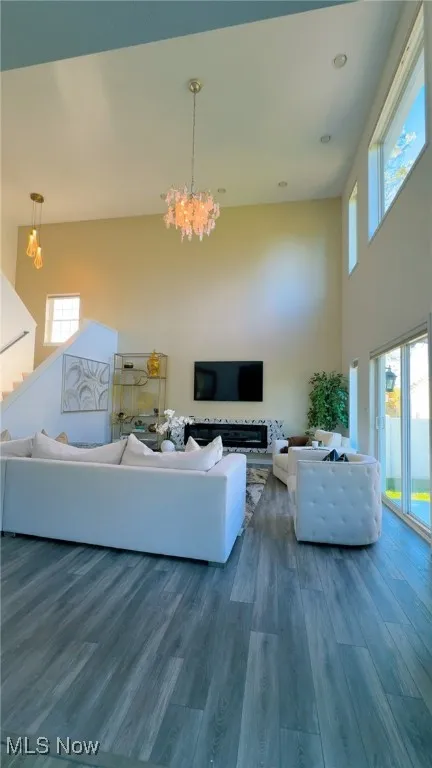 Living room featuring plenty of natural light, wood finished floors, a chandelier, and a towering ceiling