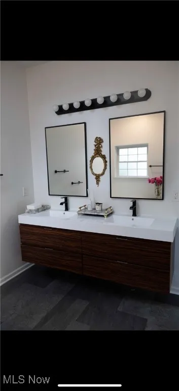 Full bath featuring double vanity and baseboards