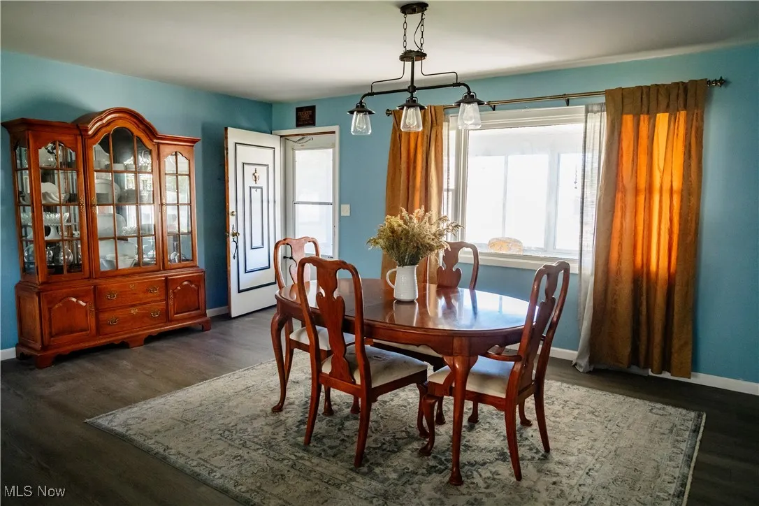 Dining area featuring dark wood-style flooring and baseboards
