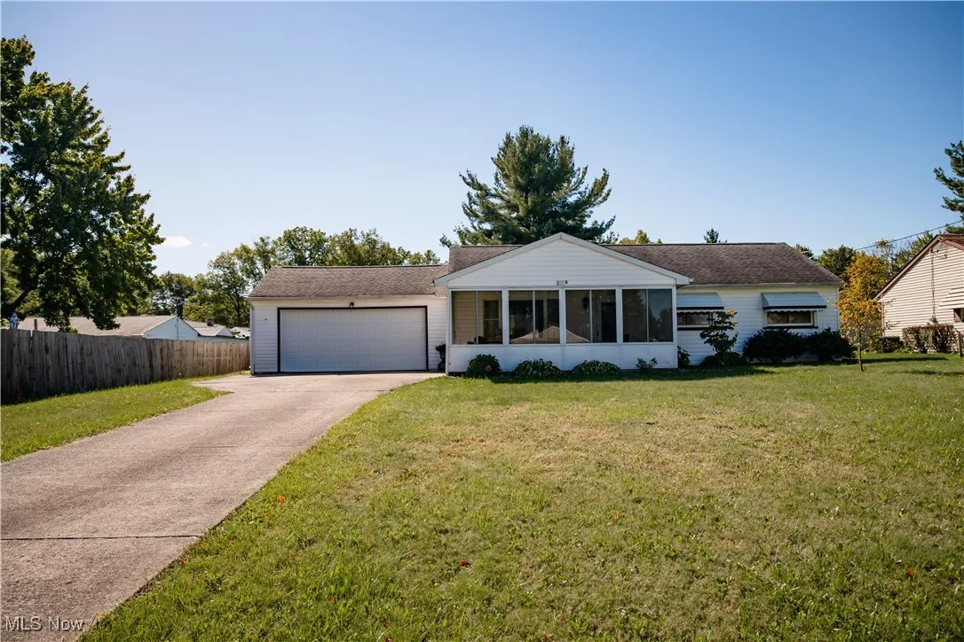 Single story home featuring a sunroom, driveway, an attached garage, and a shingled roof