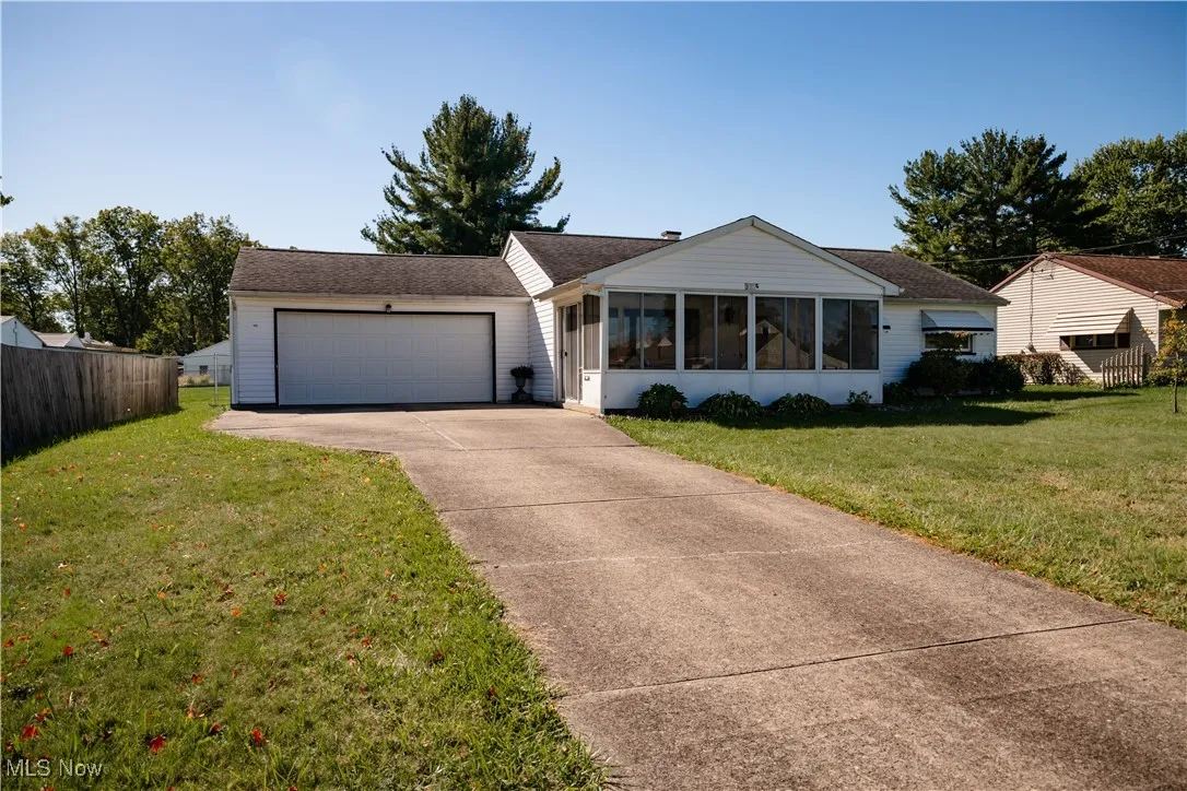 Ranch-style house with a sunroom, concrete driveway, an attached garage, and roof with shingles