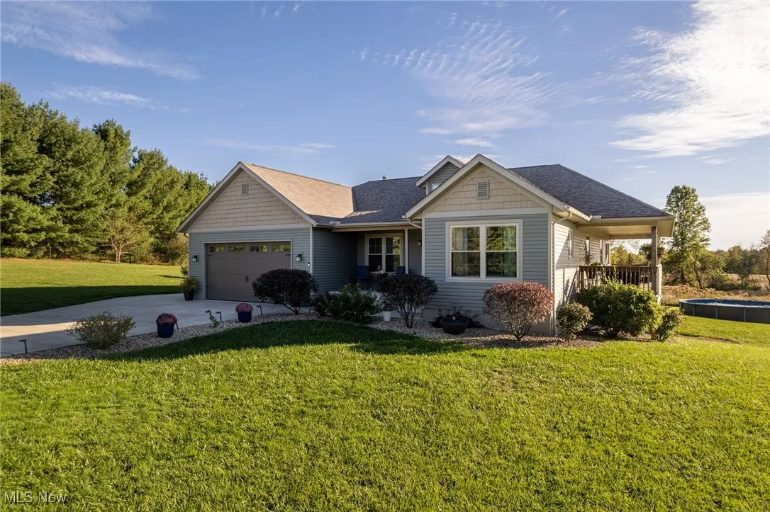View of front of property featuring a front lawn, driveway, an attached garage, and roof with shingles