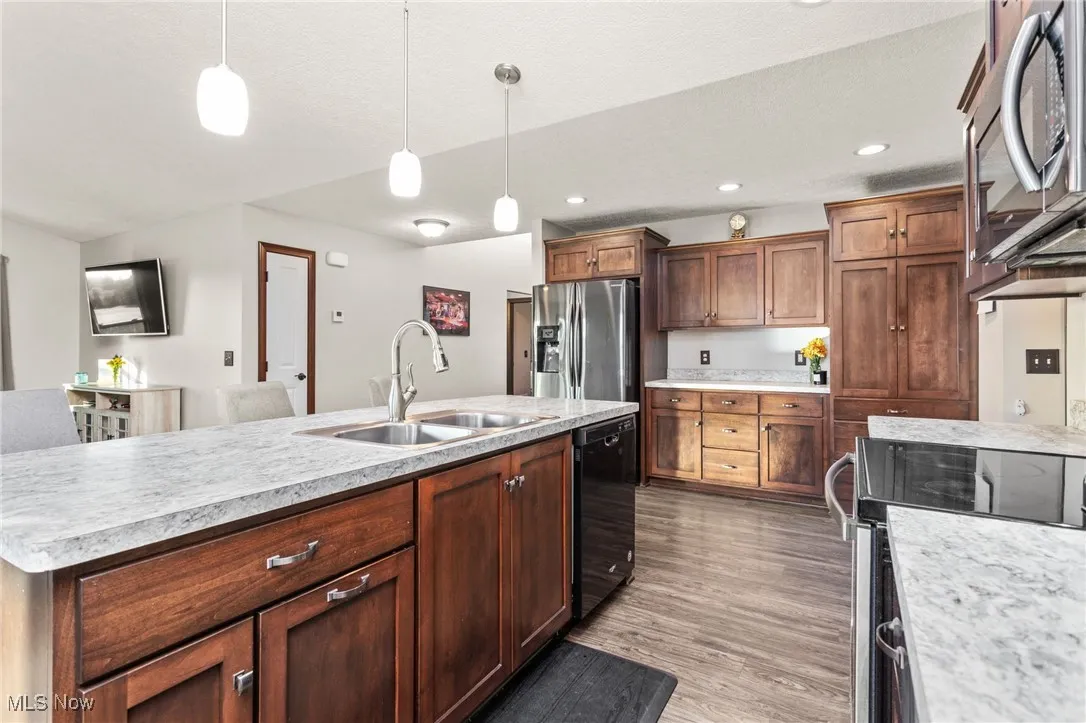 Kitchen featuring stainless steel appliances, hanging light fixtures, light countertops, dark wood-style floors, and recessed lighting
