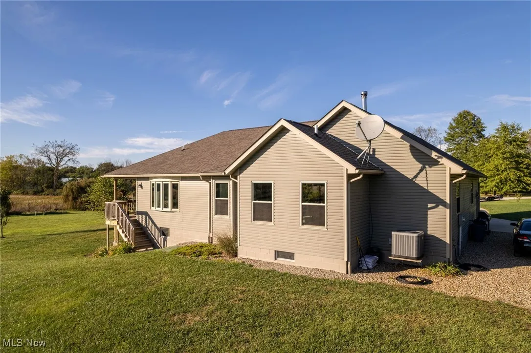 Back of property featuring a lawn, stairway, a shingled roof, and crawl space