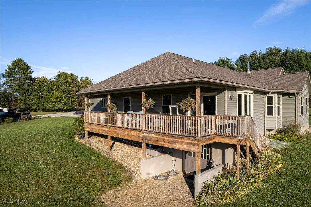 Back of house featuring a yard, roof with shingles, a deck, and stairway