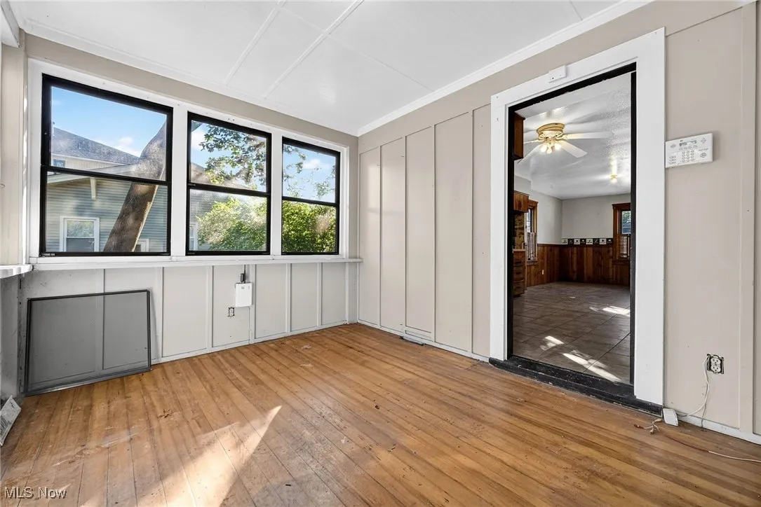 Empty room with hardwood / wood-style flooring, plenty of natural light, crown molding, a decorative wall, and ceiling fan