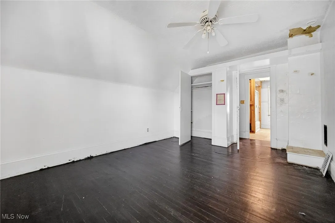 Unfurnished living room featuring dark wood-type flooring, lofted ceiling, and a ceiling fan