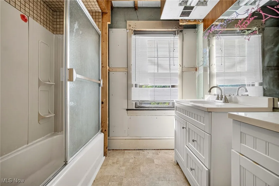 Bathroom featuring vanity and combined bath / shower with glass door