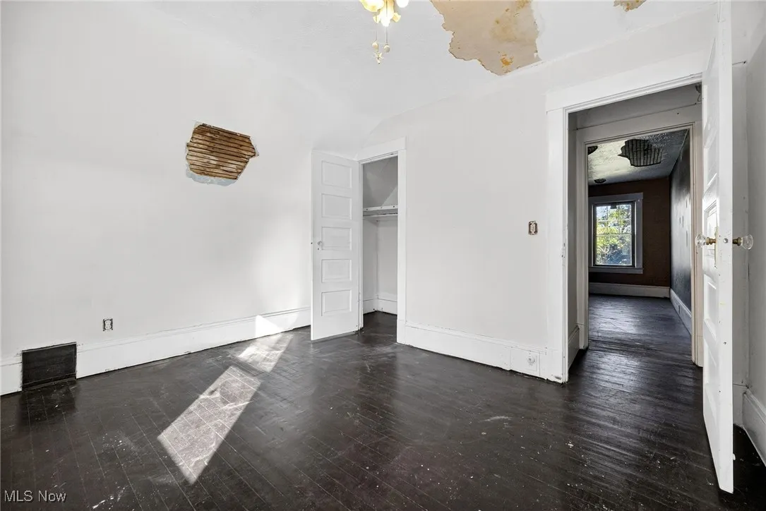 Unfurnished bedroom featuring dark wood finished floors, a closet, and lofted ceiling