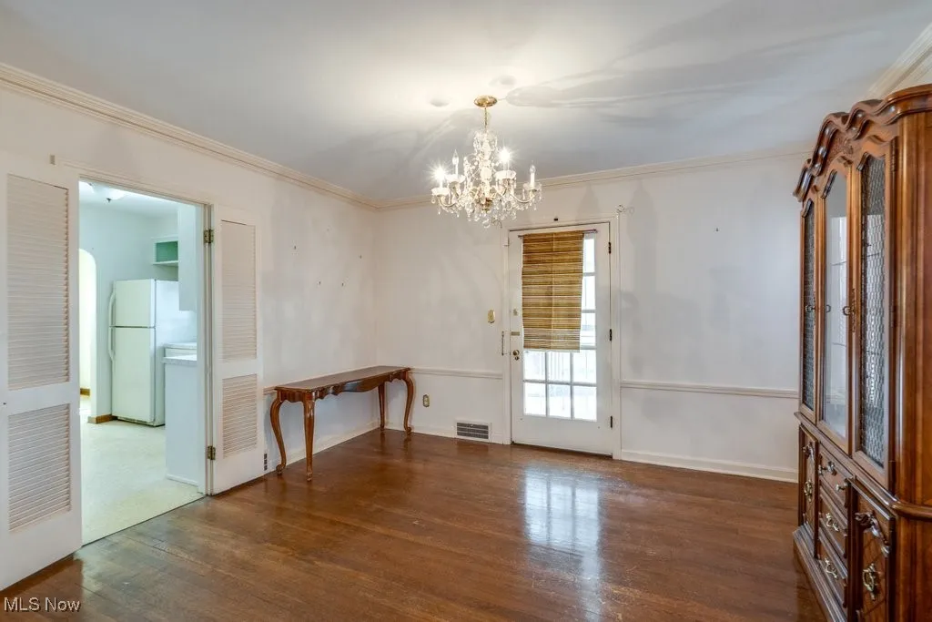 Unfurnished dining area with dark wood-style floors, and a chandelier