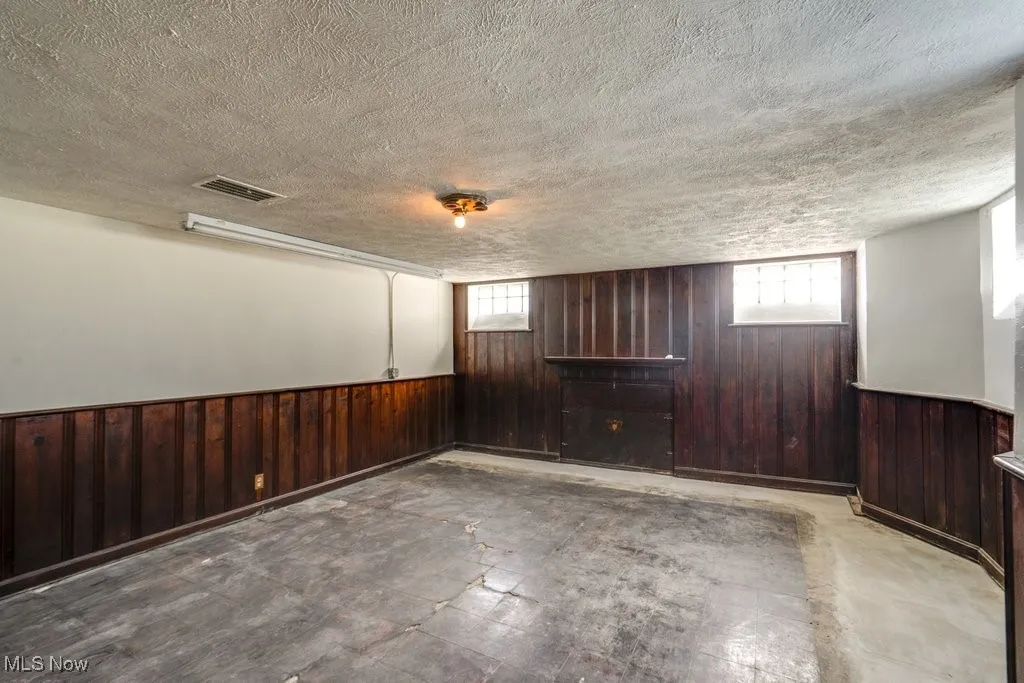Below grade area with wooden walls and textured ceiling