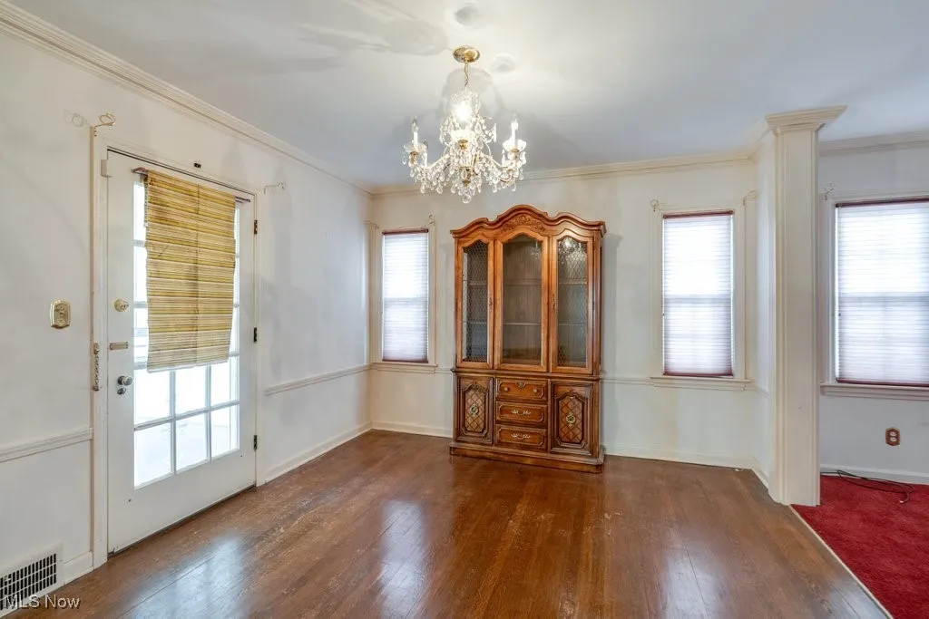 Unfurnished dining area with dark wood-type flooring, and a chandelier