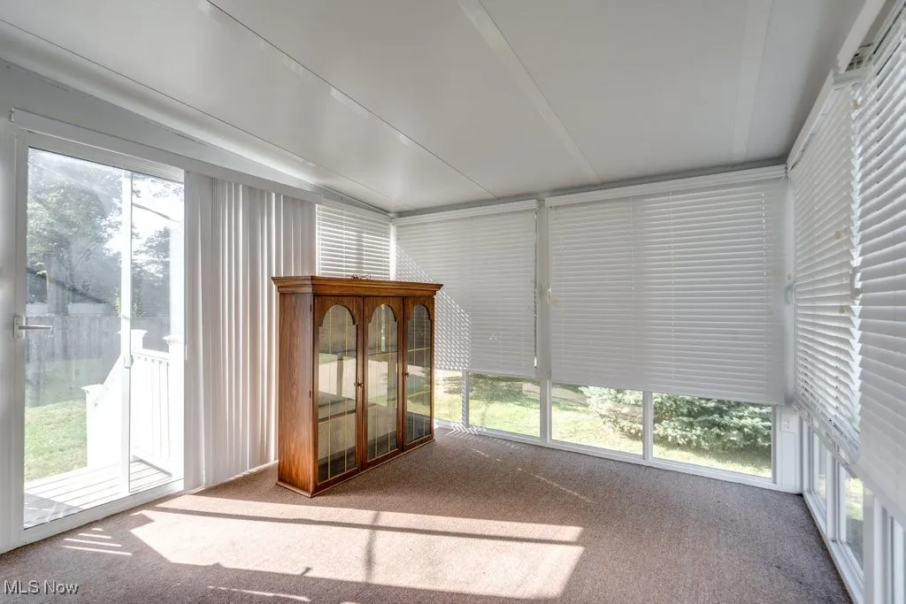 Unfurnished sunroom featuring healthy amount of natural light and carpet floors