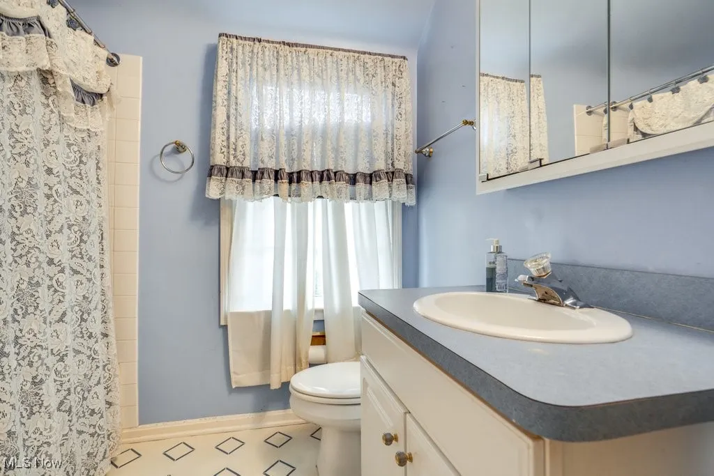 Full bath featuring vanity, curtained shower, and tile patterned floors