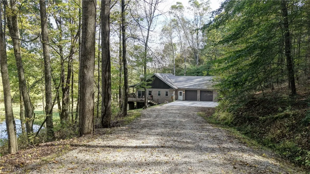 View of front of home featuring driveway and a forest view