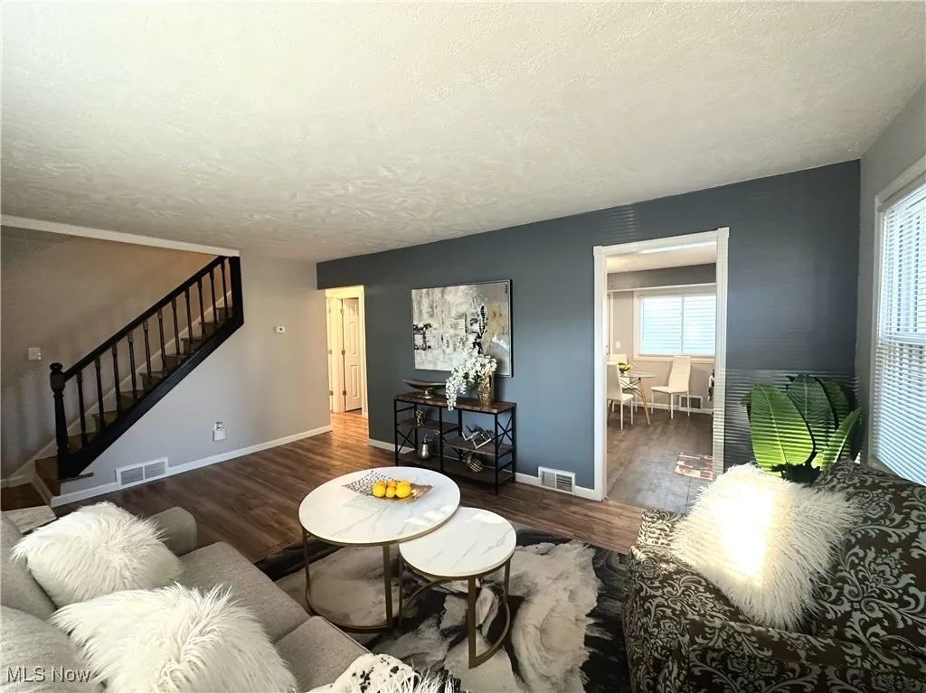 Living room featuring stairs, wood finished floors, and a textured ceiling